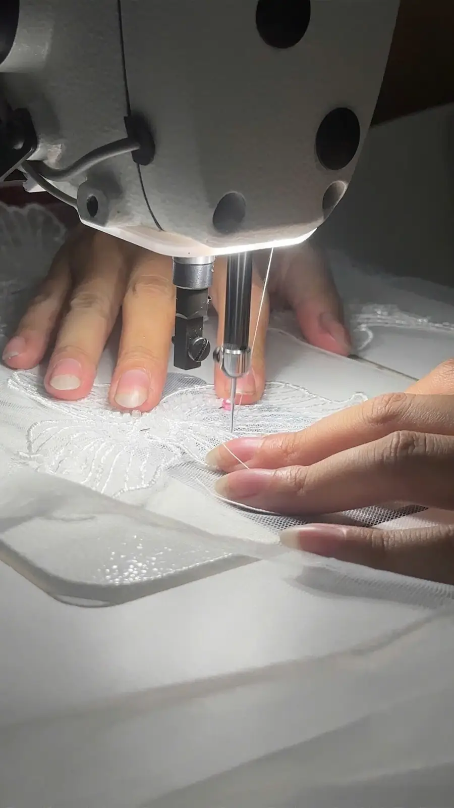 Close-up of lace being sewn under a sewing machine during VI Dressmakers atelier production
