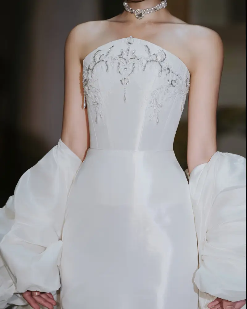 Close-up from the same reference — crystal scrollwork embroidery and pearl drops on the strapless bodice